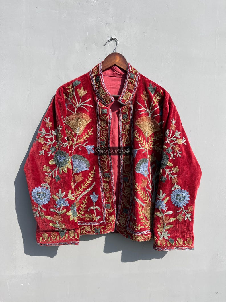 May include: A red velvet jacket with intricate floral embroidery in shades of blue, green, and gold. The jacket has a mandarin collar and a front closure.