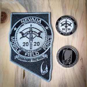 May include: A black and silver patch with the text "Nevada One Team One Fight Mobile Field 2020 Highway Patrol" and a graphic of a spear with wings. There are two silver coins with the same text and graphic, one with a black background and the other with a white background.