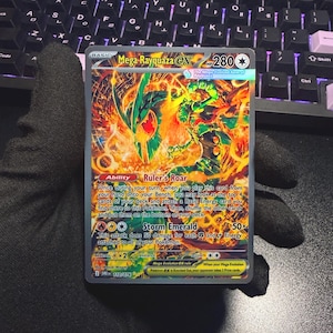Peut inclure: Une carte à collectionner Mega Rayquaza EX avec 280 PV, illustrant une créature de type dragon aux couleurs vert et orange vives. La carte présente la capacité Rugissement du Dirigeant et l'attaque Émeraude Tempête avec des textes de jeu.