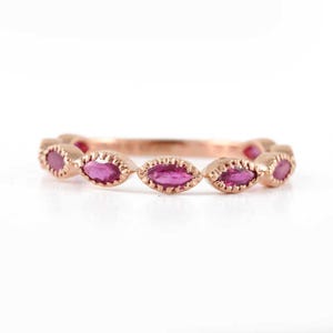May include: A rose gold band ring with a row of marquise-shaped ruby gemstones.