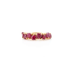 May include: A gold ring with a band of heart-shaped red gemstones. The gemstones are arranged closely together. The ring is displayed against a white background.