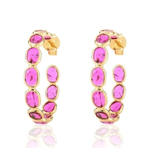 May include: Gold hoop earrings with pink oval-shaped gemstones. The earrings are approximately 5 cm in diameter.
