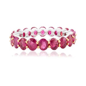 May include: A silver and gold band ring with a double row of round pink ruby gemstones.