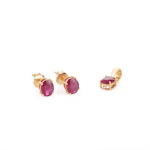 May include: A set of gold earrings and a pendant featuring red ruby gemstones.