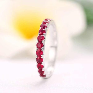 May include: A silver band ring with a row of red ruby gemstones.
