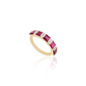 May include: A gold band ring with a row of red square-shaped rubies and smaller white diamonds set in the band.
