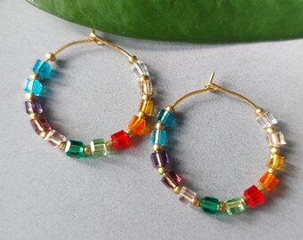 May include: A pair of gold hoop earrings with colourful square beads. The beads are arranged in a rainbow pattern, starting with red and ending with purple.
