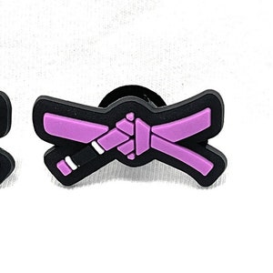 May include: Five different coloured jiu-jitsu belts, each with a black background and a white outline. The belts are white, blue, pink, brown, and black.
