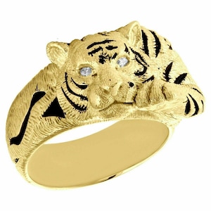 Op de afbeelding: Een gouden ring met een gedetailleerd tijgerontwerp. De ogen van de tijger zijn bezet met kleine diamanten.