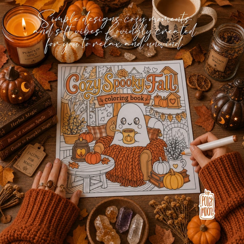 May include: A colouring book titled Cozy Spooky Fall featuring a ghost sitting in an armchair with a mug, surrounded by pumpkins and autumn decor. The book is placed on a wooden surface with a candle, a mug, crystals, and a jar of spices nearby.