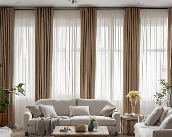 May include: A living room with a light brown sofa, two matching armchairs, a wooden coffee table, and a rug. The room has large windows with sheer curtains and brown drapes.