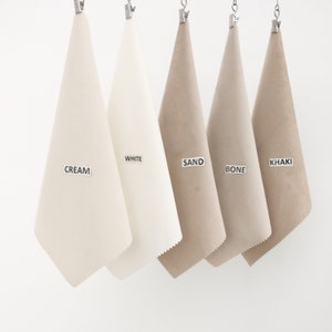 Puede incluir: Cinco muestras de tela colgadas de clips, etiquetadas como "CREAM", "WHITE", "SAND", "BONE" y "KHAKI".