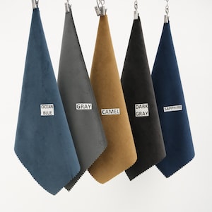 Puede incluir: Cinco muestras de tela colgando de pinzas. Las muestras son de color azul oc&eacute;ano, gris, camel, gris oscuro y zafiro.