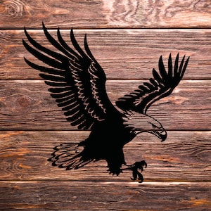 Może przedstawiać: Czarna sylwetka orła z rozpostartymi skrzydłami, osadzona na drewnianej powierzchni.