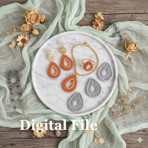 Peut inclure: Un ensemble de bijoux et d'emporte-pièces en forme de goutte d'eau sont présentés sur un plateau en marbre. Les bijoux comprennent des boucles d'oreilles, un collier, une bague et un bracelet, dans des tons orange et or. Le texte "Digital File" est visible.