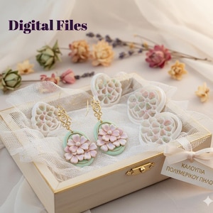Könnte beinhalten: Eine Holzkiste mit blumenförmigen Ohrringen und Formen. Die Ohrringe haben goldfarbene Verzierungen und rosa Blütenakzente auf einer hellgrünen ovalen Basis. Der Text "Digital Files" befindet sich oben links.