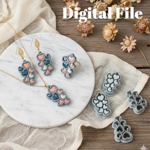 Può includere: Un set di gioielli e taglierini a forma di cuore. Il set comprende una collana, orecchini e un anello, tutti con un gruppo di cuori nei toni del blu, pesca e bianco. Il testo "Digital File" è visibile.