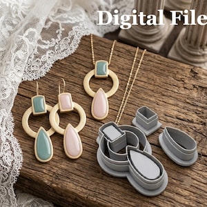 Op de afbeelding: Een sieradenset bestaande uit een goudkleurige ketting en twee oorbellen met saliegroene en lichtroze druppelvormige en rechthoekige accenten, naast drie grijze plastic uitsteekvormen met de tekst Digital File in de afbeelding.