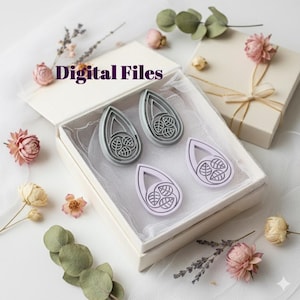 May include: A white gift box, open to reveal two grey and two lilac teardrop-shaped cookie cutters with a leaf design. The box sits on a white surface with dried flowers and the text "Digital Files".