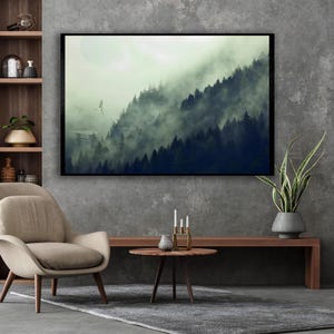 A framed canvas wall art of a misty forest landscape hangs on a textured grey wall above a console table and chair.