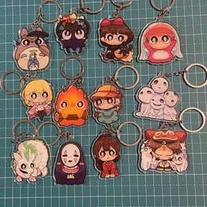 May include: A collection of anime-style character keychains. Each keychain features a different character design, with vibrant colors and detailed artwork. The keychains are attached to silver-colored key rings, perfect for fans of anime and manga.