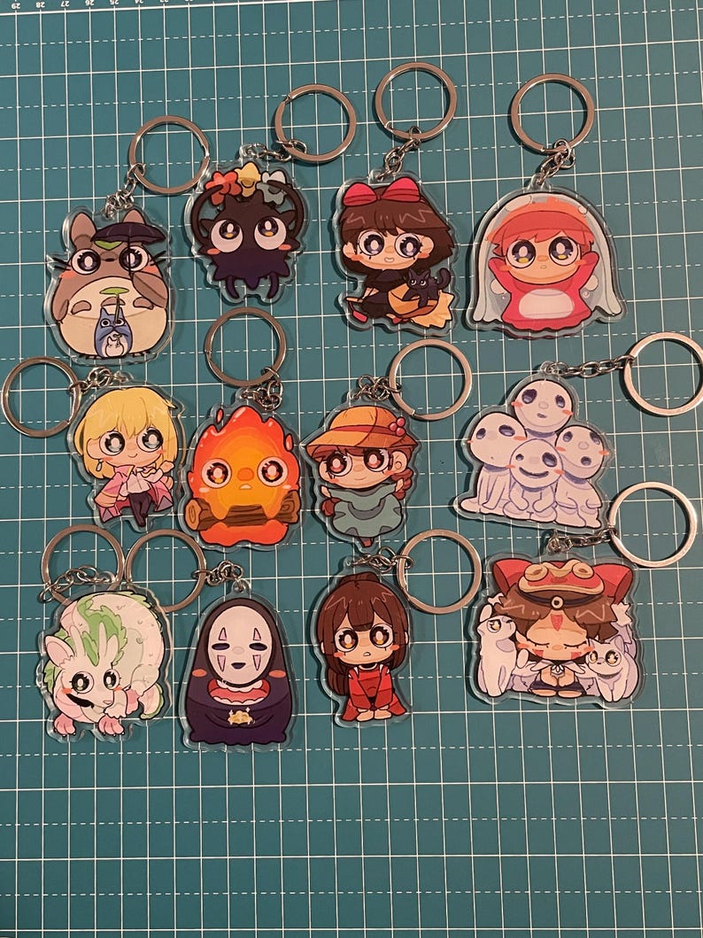 May include: A collection of anime-style character keychains. Each keychain features a different character design, with vibrant colors and detailed artwork. The keychains are attached to silver-colored key rings, perfect for fans of anime and manga.