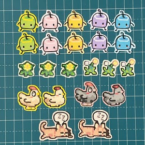Puede incluir: Una colección de pegatinas pixeladas y coloridas con varios diseños. Las pegatinas incluyen pequeñas figuras redondeadas en verde, rosa, amarillo, morado y azul, junto con flores pixeladas, pollos y perros con bocadillos. El fondo es una cuadrícula.