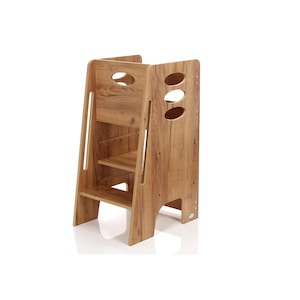 Op de afbeelding: Een houten opstapje met een natuurlijke houtnerf afwerking. De kruk heeft twee treden en een platform, met ovale uitsparingen aan de zijkant. Het ontwerp bevat een veiligheidsbeugel en is geschikt voor kinderen.
