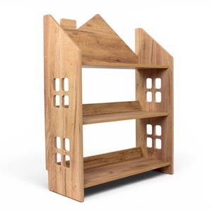 May include: A light brown wooden bookshelf shaped like a house with three horizontal shelves. The side panels feature cut-out square window designs. The structure has a peaked roof silhouette and a natural wood grain finish throughout the unit.