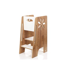 Pode incluir: Uma torre de aprendizagem em madeira com acabamento em grão de madeira natural e detalhes em branco. Possui dois degraus, um painel traseiro alto com pega recortada e painéis laterais com um recorte decorativo em forma de flor.