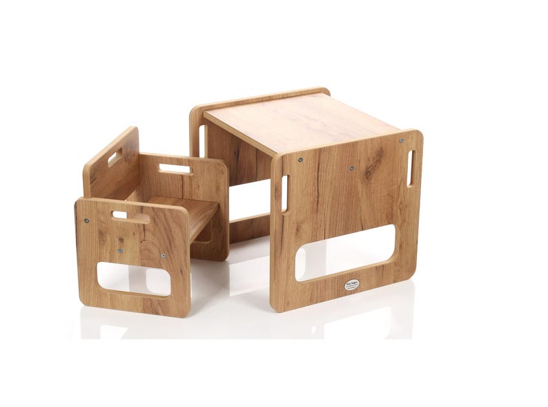 May include: A small wooden table and chair set with a light brown wood grain finish. The table has a rectangular top and the chair has a seat and back. Both have cut-out handles.