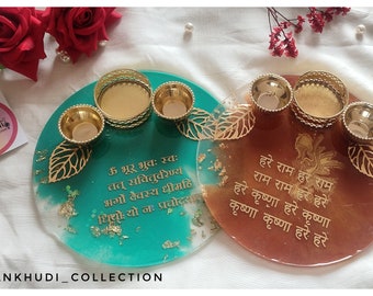 May include: Two decorative teal and brown resin candle holders with gold accents. Each holder has three gold candle cups and a gold leaf design. The teal holder has gold text and the brown holder has gold text. The brand name "PANKHUDI_COLLECTION" is at the bottom.