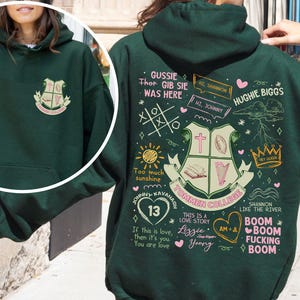 May include: Green hooded sweatshirt with a large graphic print on the back. The graphic features a crest with the text "Tommen College" and other text and illustrations including "Gussie Thor Gib Sie Was Here", "Hi Shannon", "Hi Johnny", "Hughie Biggs", "Too much sunshine", "Johnny Kavanagh 13", "This is a love story Lizzle Young", "Shannon like the river", "Boom Boom Fucking Boom", and "Am+A".