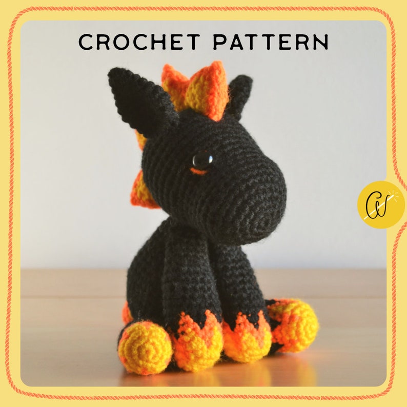 May include: A crocheted unicorn toy with a black body, orange and yellow mane, and matching feet. The image displays the text "CROCHET PATTERN". The unicorn has large black eyes and is sitting on a wooden surface.