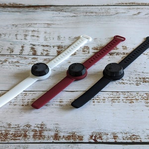 May include: Three wristbands with black, white and red bands and black round buttons.