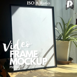 May include: A black picture frame mockup with a white background. The frame is sitting on a wooden table with a potted plant in the background. The text "Video Frame Mockup" is written in white on the table.