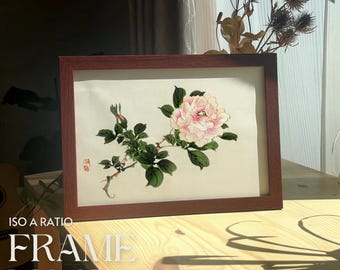 Op de afbeelding: Een bruin houten frame met een witte passe-partout en een delicate aquarel van een roze bloem met groene bladeren. Het schilderij is getiteld "174"