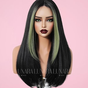 May include: A long, black wig with two streaks of light green hair framing the face. The wig is styled on a mannequin head with a pink background. The text "LUNARA WIGS" is visible at the base of the mannequin.