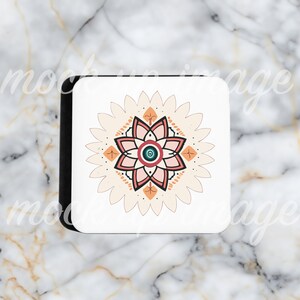Pode incluir: Base quadrada branca com borda preta, com um design floral simétrico. O design inclui uma flor rosa no centro, rodeada por um fundo creme com detalhes em laranja e turquesa. A base está sobre uma superfície de mármore.