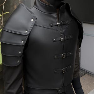 以下が含まれることがあります： 黒い革のベストと肩当て。 ベストはハイカラー、ジッパー開閉、前面に3つのバックルストラップが付いています。 肩当ては重ね着され、シルバーのリベットで固定されています。 ベストは濃い単色です。