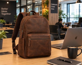 May include: A brown leather backpack featuring a large main compartment and a smaller front pocket, both secured with metal zips. The backpack has adjustable shoulder straps and a top handle, showcasing a smooth, matte finish with visible texture.