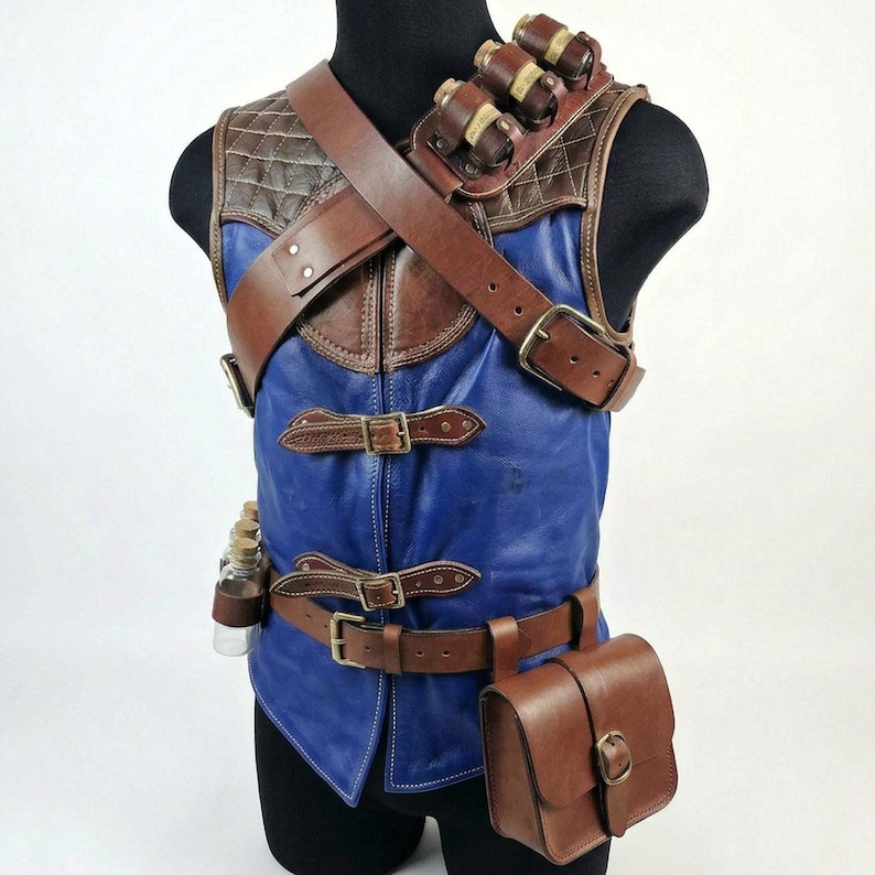 May include: A blue and brown leather vest with multiple pouches, straps, and buckles. The vest features a quilted shoulder piece and a brown leather strap across the chest. Small glass bottles are attached to the vest.