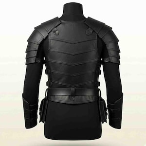 Puede incluir: Una pieza de armadura de pecho de cuero negro con hombreras superpuestas, una placa de torso segmentada con paneles en forma de V, un cintur&oacute;n con bolsas laterales integradas y brazaletes a juego, asegurados con correas y hebillas ajustables.