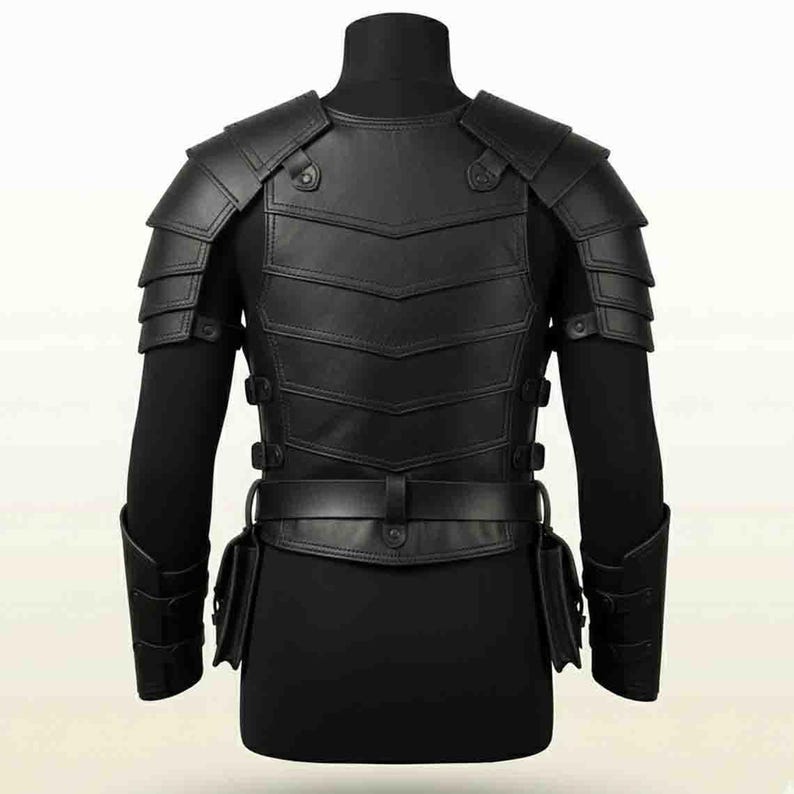 Puede incluir: Una pieza de armadura de pecho de cuero negro con hombreras superpuestas, una placa de torso segmentada con paneles en forma de V, un cintur&oacute;n con bolsas laterales integradas y brazaletes a juego, asegurados con correas y hebillas ajustables.