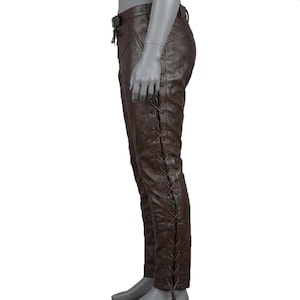 May include: Brown leather pants with a lace-up design on the side. The pants have a belt and a fitted silhouette. The leather appears to have a textured finish. The pants are displayed on a mannequin.