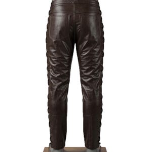 May include: Brown leather pants with a lace-up design on the sides. The pants have two back pockets and a classic fit. The leather has a slightly distressed look.