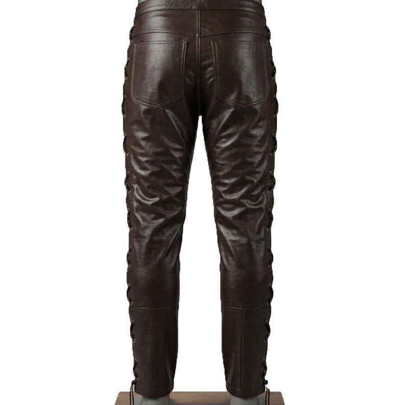 May include: Brown leather pants with a lace-up design on the sides. The pants have two back pockets and a classic fit. The leather has a slightly distressed look.