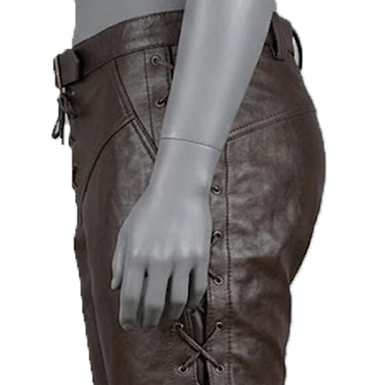 May include: Brown leather pants with a belt and lace-up detailing on the sides. The pants have a classic design with visible stitching and a fitted silhouette. The leather appears to be of high quality, with a slightly textured surface.