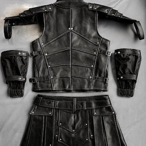 May include: A black leather armor set, including a vest, skirt, shoulder armor, and two arm guards. The vest and skirt have a geometric design with silver rivets. The arm guards have elastic cuffs. The set is laid out on a gray surface.