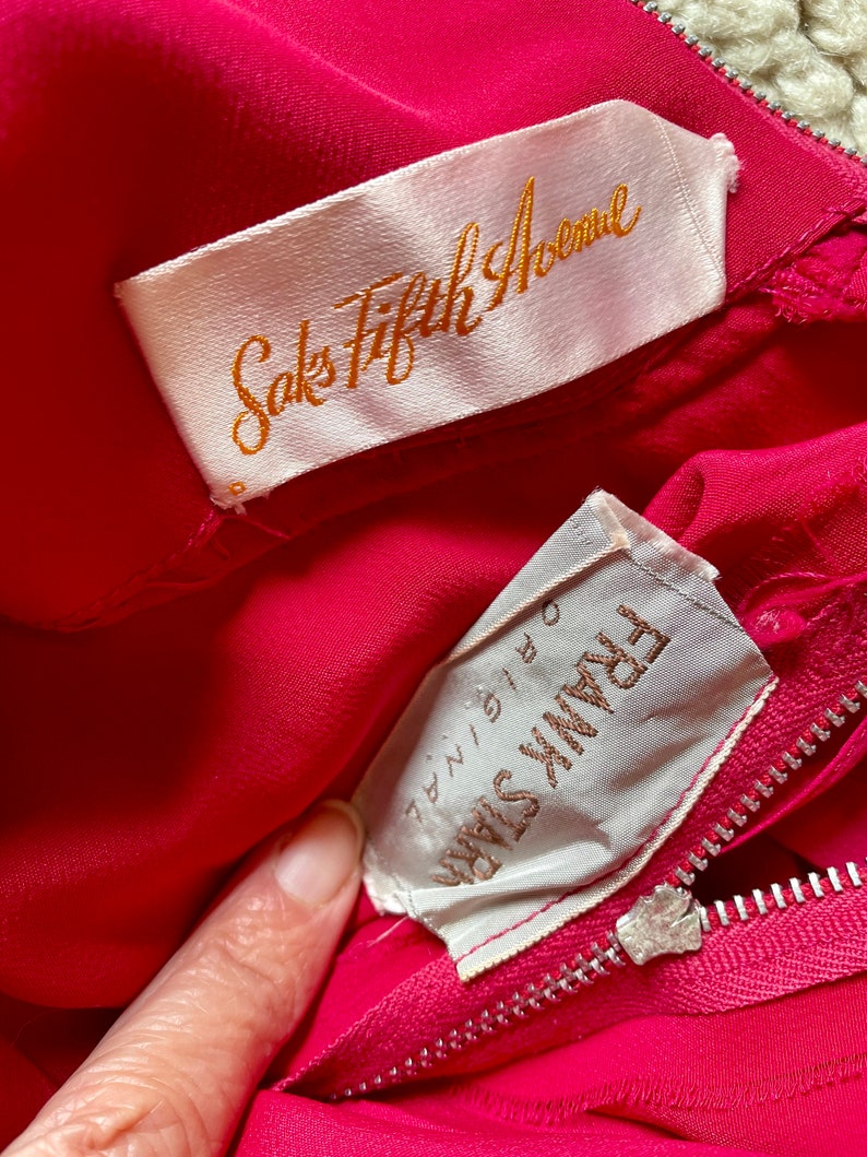 May include: A pink silk dress with a white label that says "Saks Fifth Avenue" and a white label that says "Frank Starr" with the size "7/8" written on it.